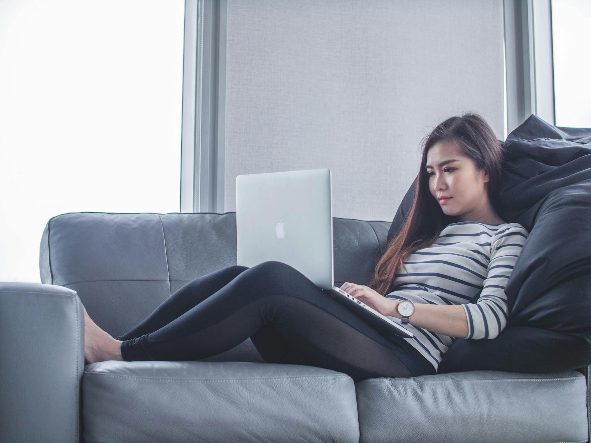 Women sat on a couch happily using her computer